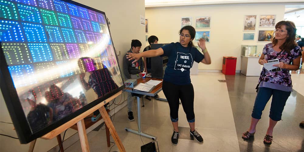 student showing off an engineering project of a LED lighted board.