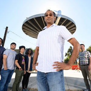 A professor and his students stand near a solar array