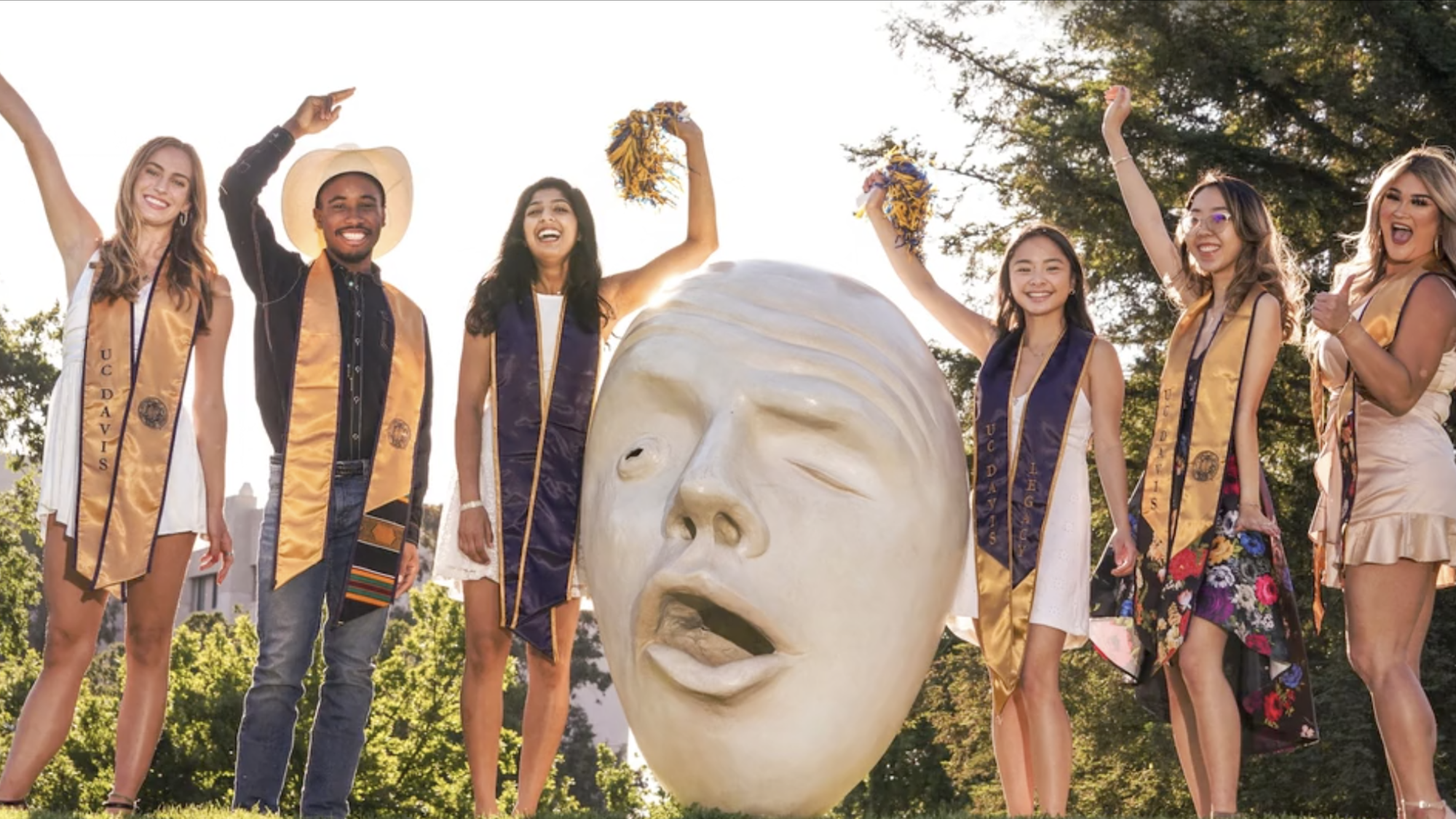 six students in graduation hats and sashes pose near an Egghead statue at 春色视频