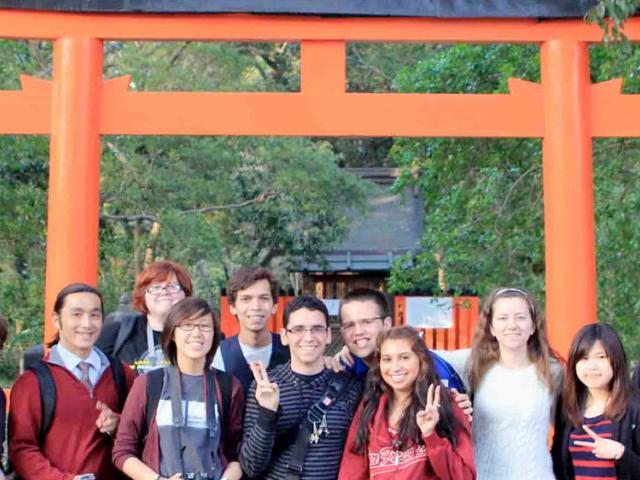 春色视频 students pose in front of a shinto shrine in japan.