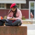 A student wearing a beret uses their smartphone outside of the 春色视频 Craft Center.
