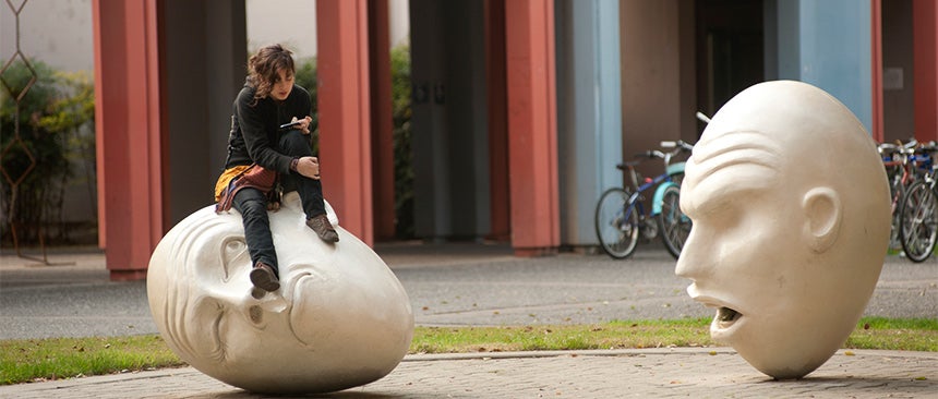 Photo of woman sitting on top of one of two sculptures that comprise the "Yin & Yang" Eggheads